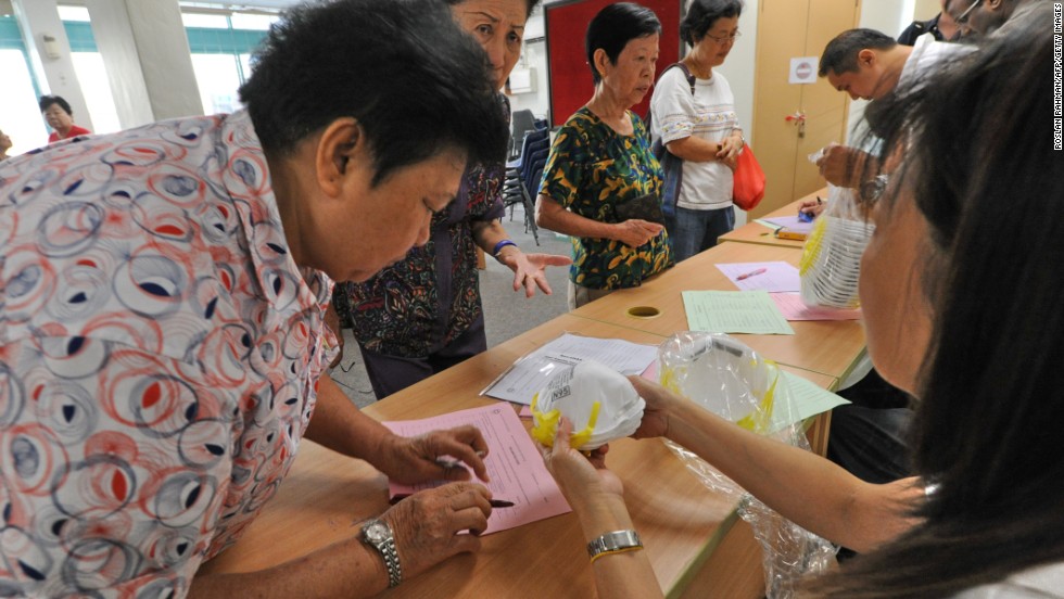 Elderly people sign up to collect face masks at the community centre for the low income in Singapore on June 22, 2013.