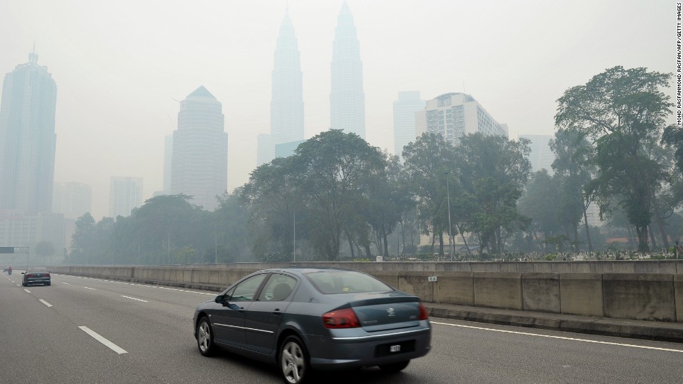 Motorists drive as haze shrouds Malaysia&#39;s landmark Petronas Twins Towers in Kuala Lumpur on June 23. The Malaysian government declared a state of emergency on June 23 in two southern areas.