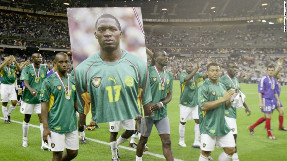 Cameroonian players join 2003 Confederations Cup champions France on a lap of honor, bearing an image of Foe -- whose medal is hanging off his portrait.