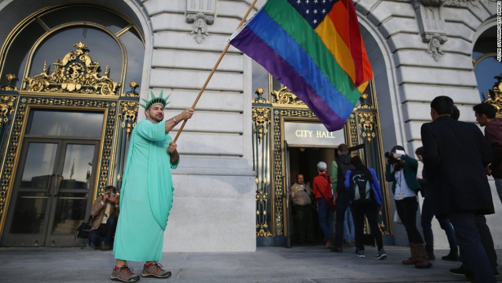 A gay rights supporter waves a flag outside City Hall in San Francisco ahead of the Supreme Court decisions on June 26.