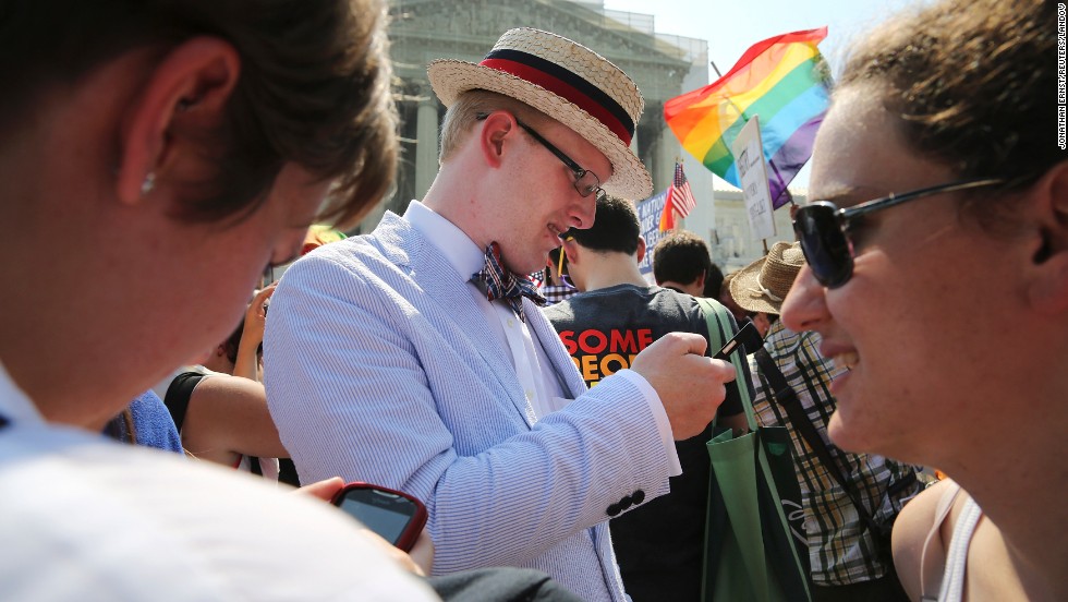 Same-sex marriage proponent Ryan Clarke reads news updates on the rulings outside of the Supreme Court.