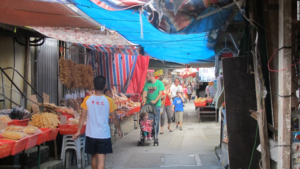 Tourists walk down Tai O&#39;s main street, where locals operates seafood stores and souvenir shops.