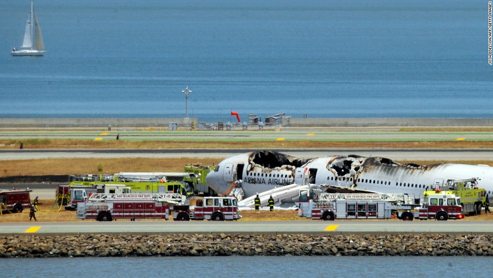 The burned-out plane sits surrounded by emergency vehicles on July 6.
