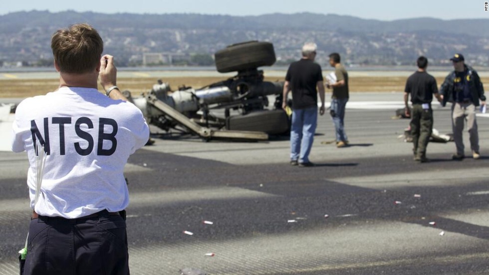 An investigator photographs part of the landing gear at the crash site in a handout released on July 7. Investigators believe that the pilots were flying too slow and too low as they neared the airport on July 6.  