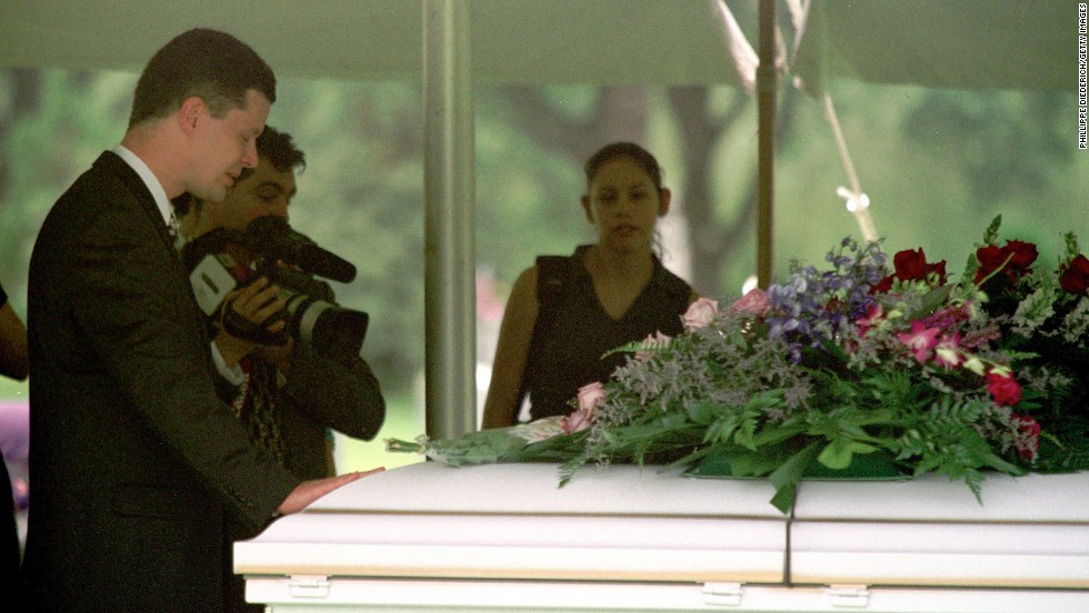 Russell Yates places his hand on the casket of one of his deceased children during their funeral on June 27, 2001, at Forest Park East Cemetery in Houston. On July 30, 2004, he filed for divorce from Andrea.