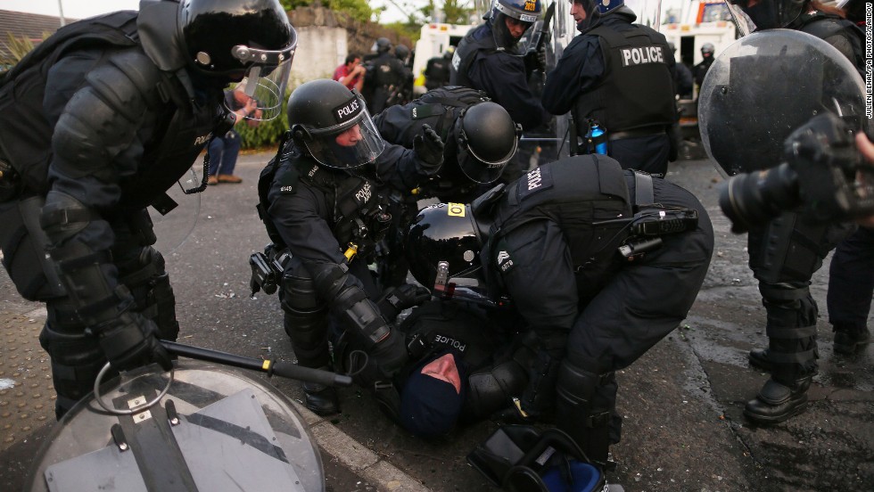 Riot police help an injured officer as they try to contain protesters on Friday, July 12.