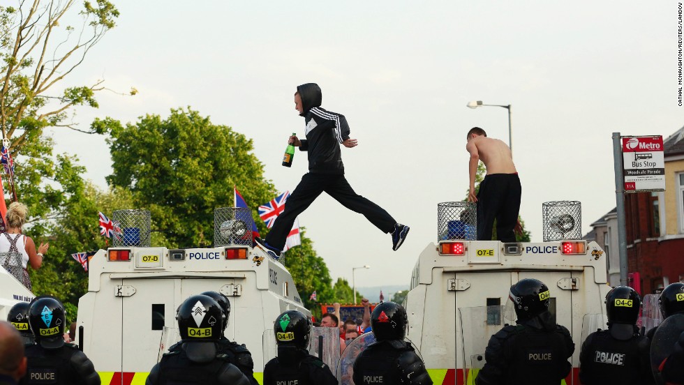 Protesters climb onto police vehicles in the Woodvale Road area of Belfast on July 12.