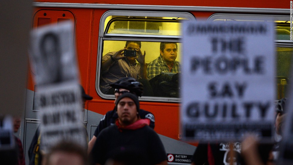 A passenger takes a picture of protesters as he rides a city bus on July 16 in Los Angeles.