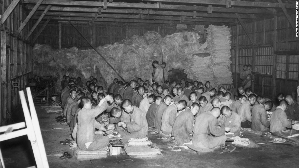 North Korean prisoners of war make baskets on the floor of a storage barn at a prison, circa 1951.