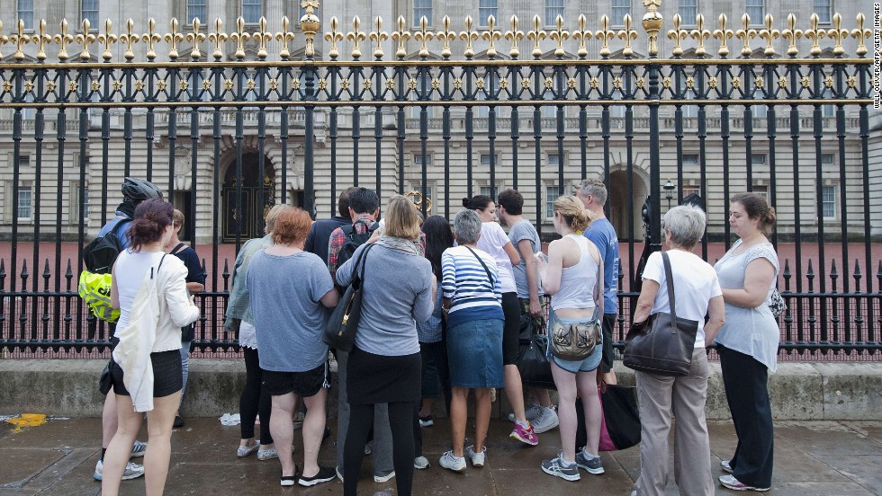 People gather outside Buckingham Palace in London on July 23 to read the notice announcing the birth of the royal baby. The news was placed in the forecourt of Buckingham Palace on July 22.