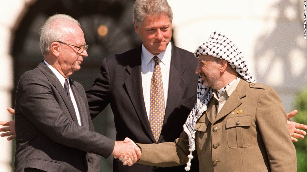 US President Bill Clinton (C) stands between PLO leader Yasser Arafat (R) and Israeli Prime Minister Yitzahk Rabin (L) as they shake hands on September 13, 1993, at the White House in Washington DC. Rabin and Arafat shook hands for the first time after Israel and the PLO signed a historic agreement on Palestinian autonomy in the occupied territories. 