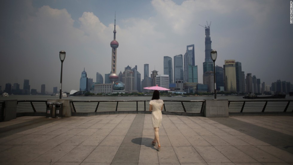 A woman uses a parasol to block the sun&#39;s rays at the Bund, a popular tourist spot in Shanghai, China, on August 7. 
