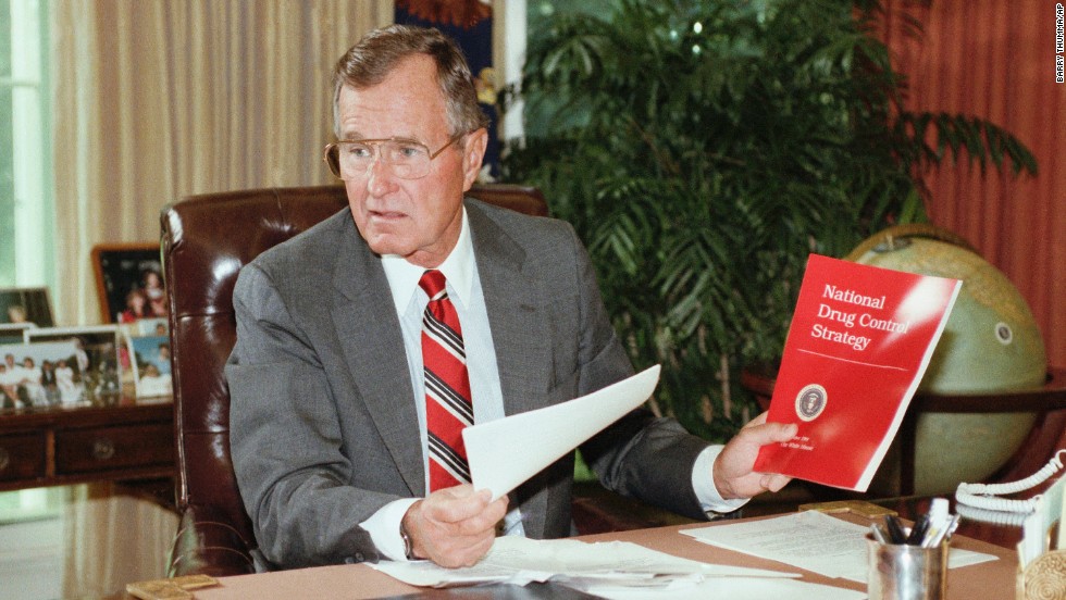 President George H. Bush holds up a copy of the National Drug Control Strategy during a meeting in the Oval Office on September 5, 1989. In a televised address to the nation, Bush asked Americans to join the war on drugs.