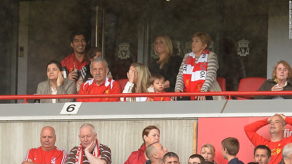 A smiling Luis Suarez (back left) attends Liverpool&#39;s opening fixture of the Premier League season. The Uruguayan striker is serving the fifth game of a 10-match ban for biting Branislav Ivanovic in a match against Chelsea last April. Suarez&#39;s future at Liverpool is in doubt following an acrimonious summer in which the striker has agitated for a move away from Merseyside. Liverpool insist the player is not for sale.