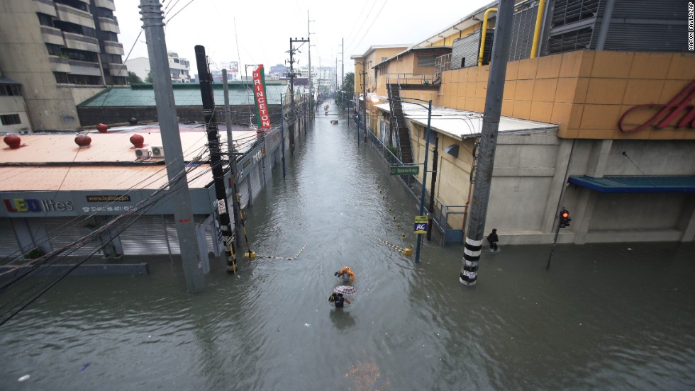 People wade through a flooded street in Makati on August 20.