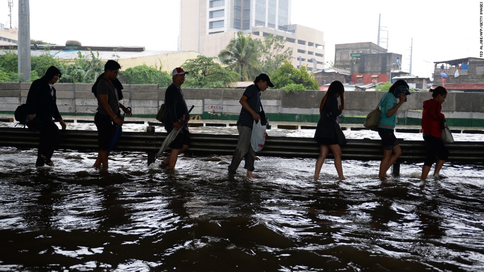 People walk along a flooded highway as heavy rains hit Manila on August 20.