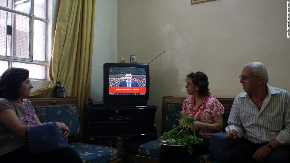 Syrians listen to a televised speech by al-Assad in Damascus on June 3, 2012. Al-Assad said that his government faces a foreign plot to destroy Syria and blamed &quot;monsters&quot; for the Houla massacre in a rare televised speech delivered in parliament. 