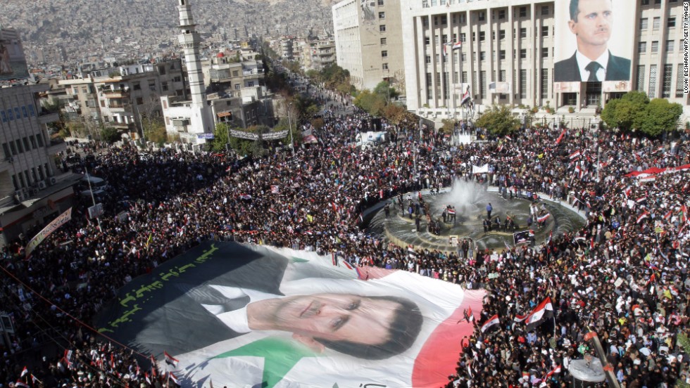Syrian demonstrators carry a giant portrait of al-Assad in Damascus on November 28, 2011. Protesters waved Syrian flags and chanted nationalist songs in a demonstration against the Arab League&#39;s decision to impose crippling sanctions on the Assad regime.