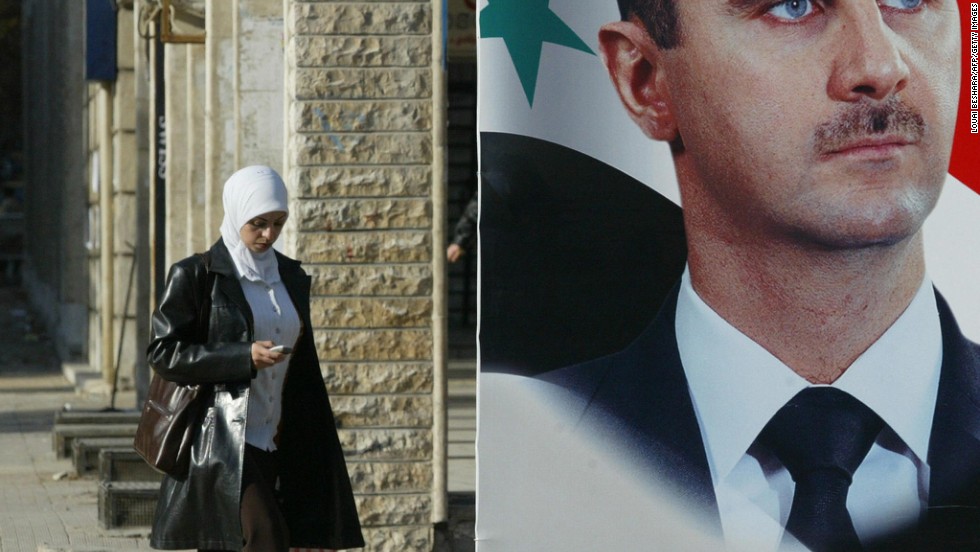 A Syrian woman walks past a large portrait of President al-Assad in downtown Damascus on December 13, 2005.