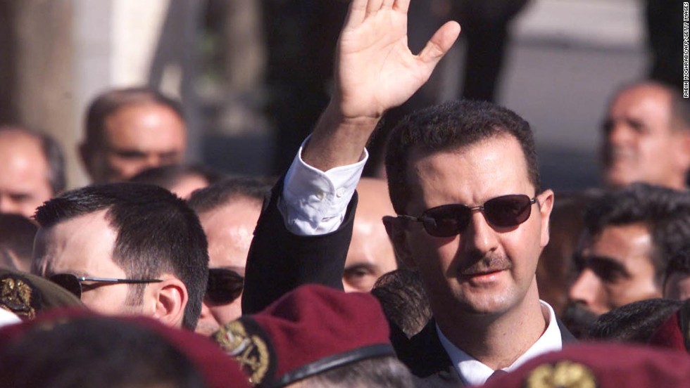 Al-Assad waves to supporters as he marches behind the coffin during his father&#39;s funeral in Damascus on June 13, 2000.