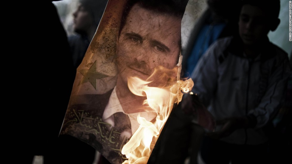 A member of the Free Syrian Army holds a burning portrait of al-Assad near the flashpoint city Homs on January 25, 2012.