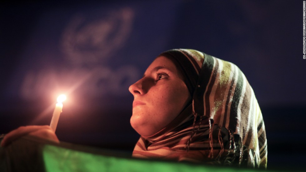 A young woman holds a Syrian revolution flag and a candle during a protest of President Bashar al-Assad in front of the U.N. headquarters in Gaza City on Friday, August 23. U.N. Secretary-General Ban Ki-moon intends to conduct a &quot;thorough, impartial and prompt investigation&quot; into the alleged chemical weapons attack in Syria.