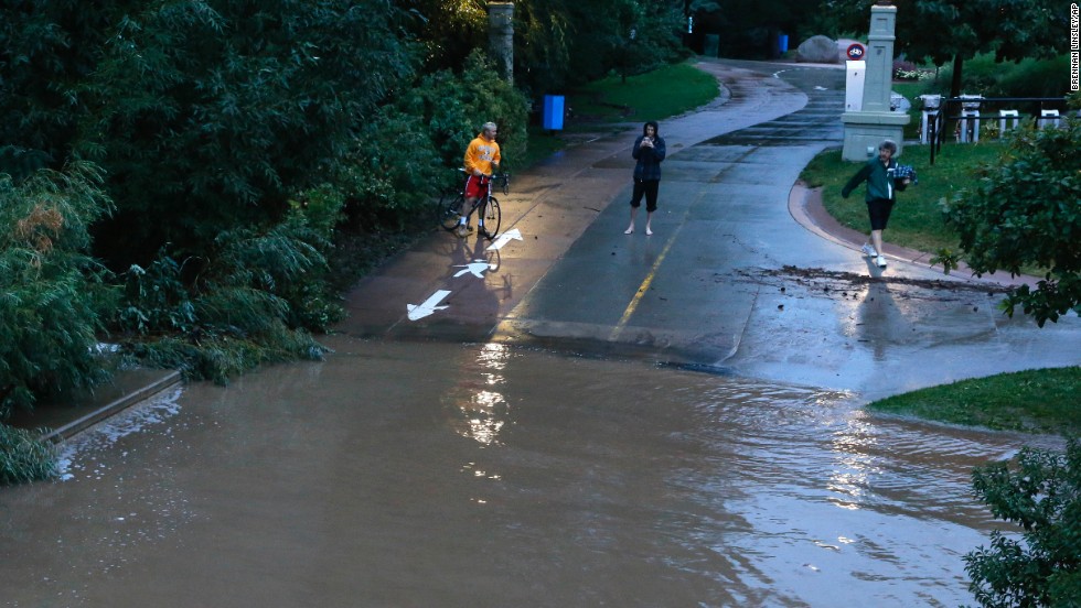 People stand at the edge of floodwaters in Boulder on September 12.