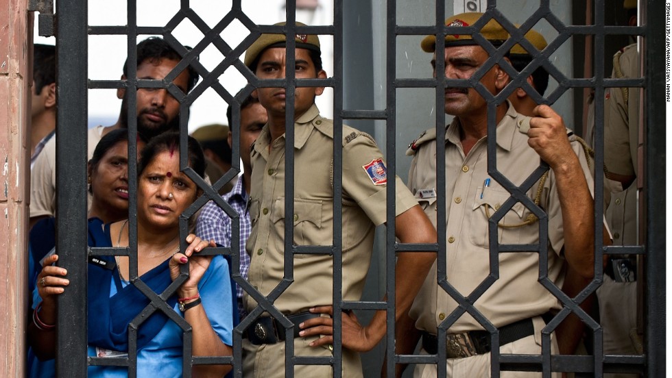 Indian court staff and police officers watch demonstrators shout slogans after the sentencing at the Saket courthouse in New Delhi.