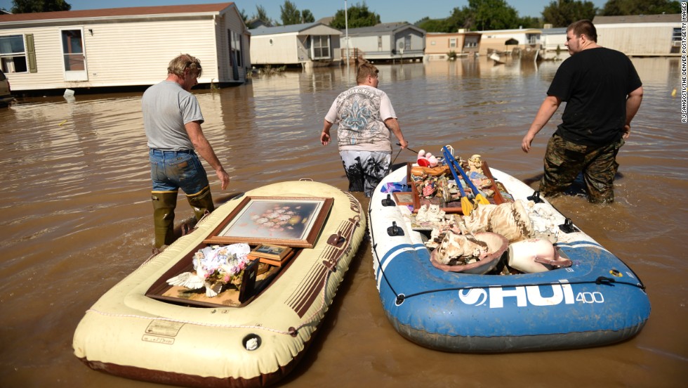 From left, Dale Reeves, Kathryn Reeves and Trent Mayes assist a family member by moving belongings from a flooded home in Evans, Colorado, on September 17.