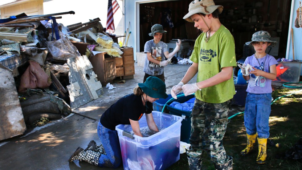 From left, siblings Elizabeth, 13, Jonathan, 9, Aaron, 11, and Kitty Dipert, 6, wash mud from the clothing of family friends from church on September 18 in Longmont, Colorado.