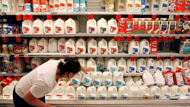 A customer scans the expiration date on gallons of milk sitting at a Safeway grocery store in Washington.