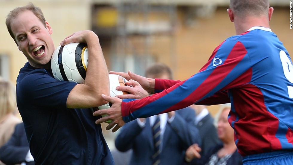 Prince William is clearly enjoying himself as he wrestles to keep the ball during a training session at Buckingham Palace. 