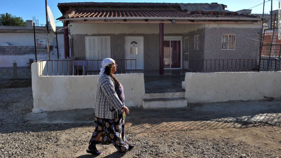 A Roma woman walks next to the house where the family lived in Farsala. A spokesman for Smile of the Child, the charity that took Maria in, said the girl was found in &quot;bad living conditions, poor hygiene.&quot;