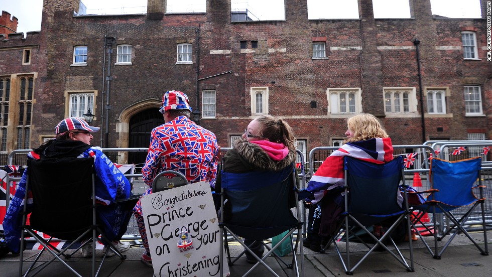 Spectators sit across from St. James&#39; Palace as they wait for the royal family to arrive for the christening. 
