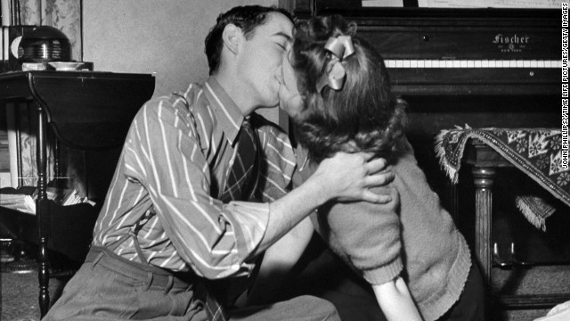 A couple of teens kiss during a game of spin the bottle at a party in 1942.