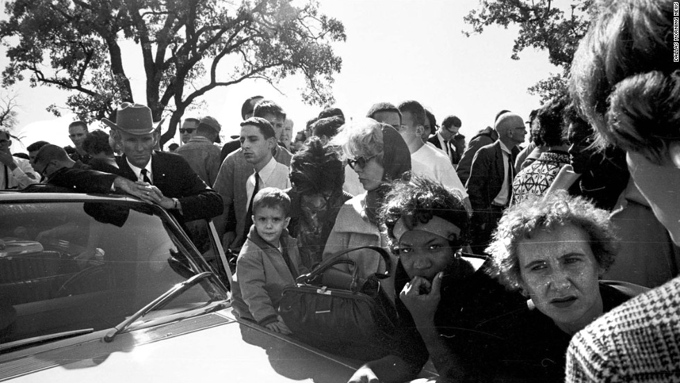 Hurchel Jacks, Vice President Johnson&#39;s driver in the motorcade, listens with others to news accounts on the car radio outside the Parkland Hospital emergency entrance. After the shots were fired, Jacks had rerouted the vice president&#39;s car to safety. The ABC radio network broadcast the first nationwide news bulletin reporting that shots have been fired at the Kennedy motorcade.