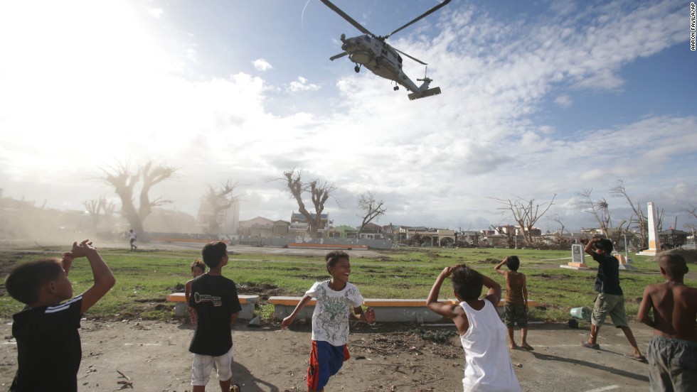 Typhoon survivors watch as a U.S. helicopter lands to deliver relief goods in Tanauan, Philippines, on Wednesday, November 20.  