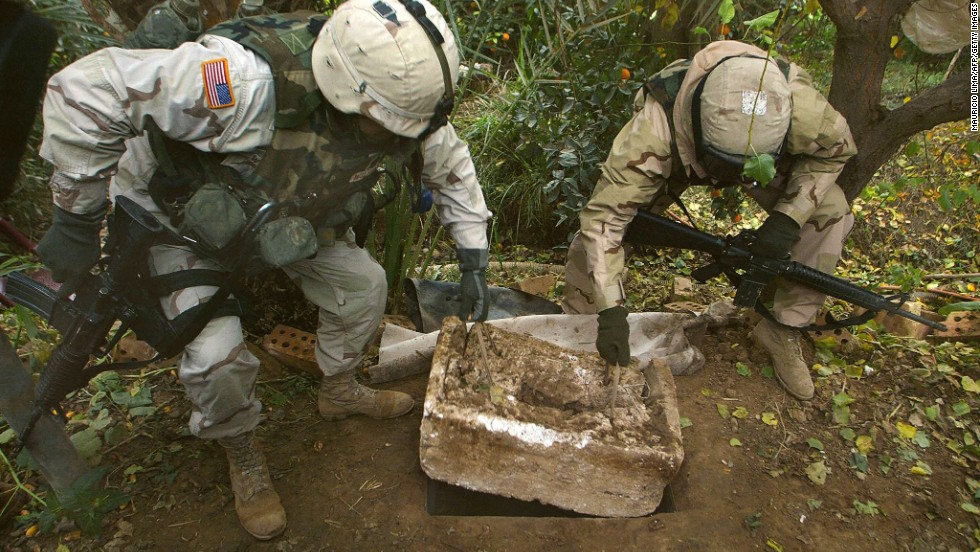 Two U.S. soldiers show the hole where Hussein was captured.