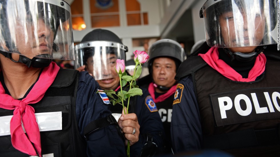 A Thai riot policeman holds flowers which were offered to him by opposition protesters during a rally at a government complex in Bangkok on November 27, 2013.