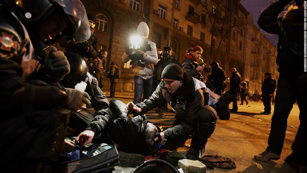 Police and protesters look at an injured person near the presidential office on December 1. 