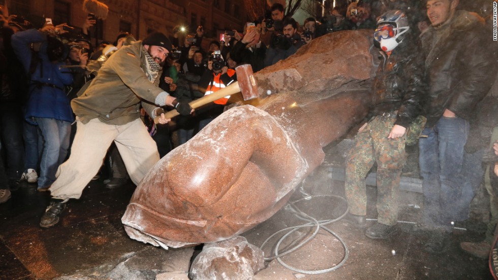 A protester in Kiev slams a toppled monument of Vladimir Lenin on December 8.