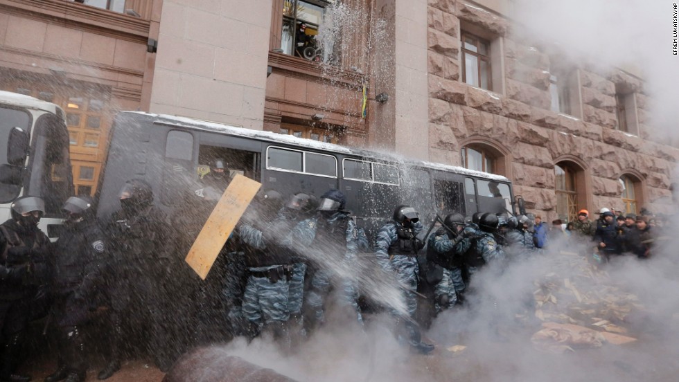 Riot police officers block the entrance of Kiev&#39;s City Hall as protesters pour water from windows and throw smoke grenades at them on December 11.