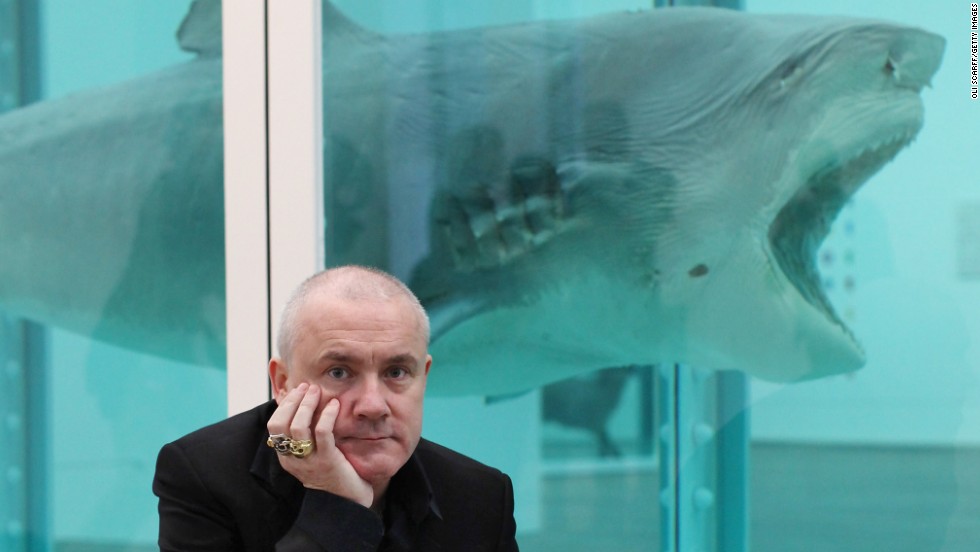 Damien Hirst, seen here in front of one of his most famous artworks, &quot;The Physical Impossibility of Death in the Mind of Someone Living&quot; - a shark preserved in formaldehyde - was the subject of a major retrospective at London&#39;s Tate Modern gallery in 2012. 