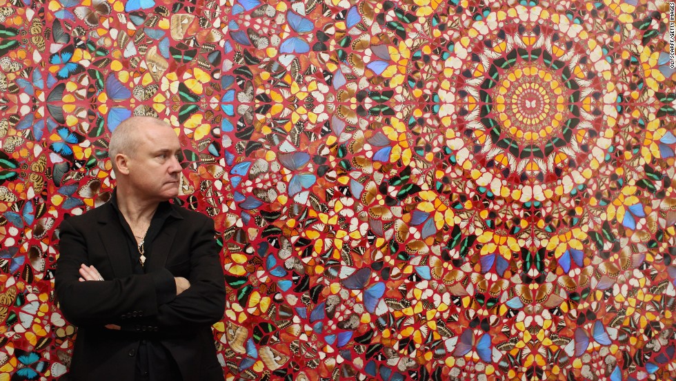 Hirst, possing in front of his artwork &quot;I am Become Death, Shatterer of Worlds&quot; at London&#39;s Tate Modern on April 2, 2012, rose to fame in the 1990s as one of the Young British Artists, or YBAs, along with Tracey Emin, Sarah Lucas and Jake and Dinos Chapman. 