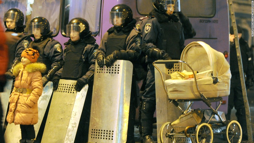 A young girl stands next to police officers guarding the presidential offices in central Kiev on December 17.