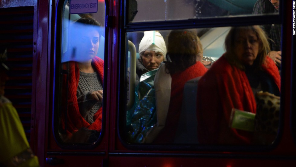 Injured people sit on a bus used for theatergoers.