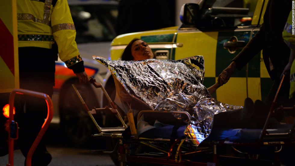 An injured woman is taken toward a waiting ambulance.