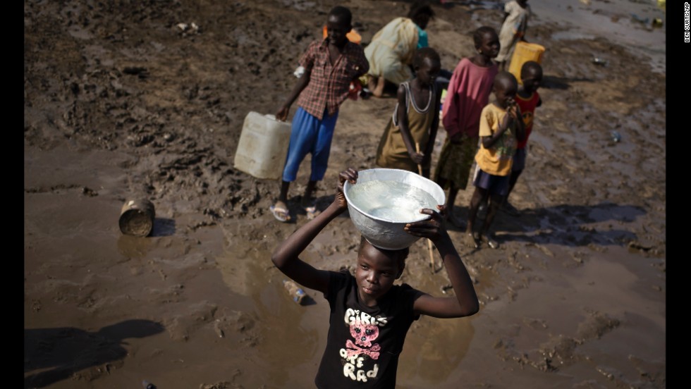 A girl carries a bowl of water after filling it from a truck at the U.N. compound in Juba on December 29.