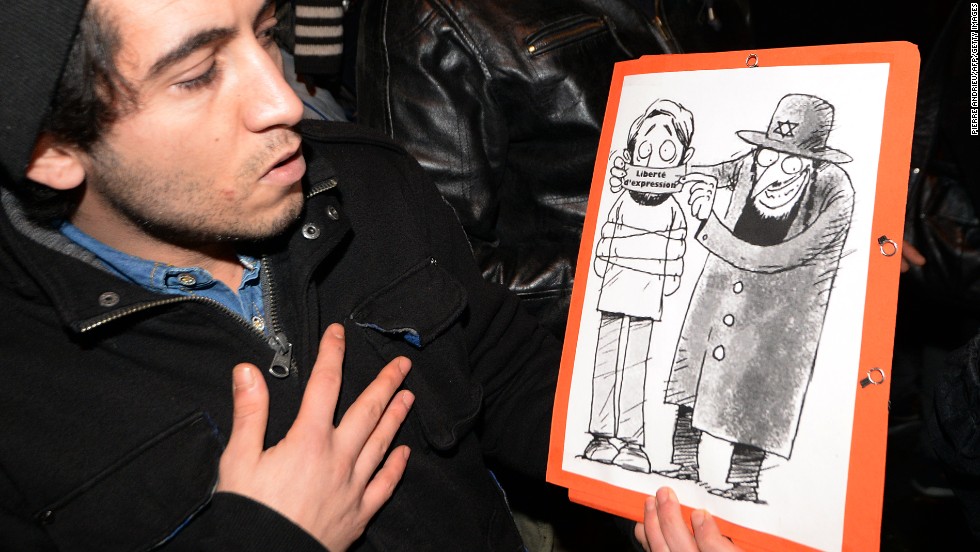 Supporters of Dieudonne  argue that the issue of &quot;freedom of speech&quot; in France is at stake after Valls called for the comic&#39;s performances to be banned. Here a man poses with one of his drawings showing a Jewish character covering the mouth of another character with a gag reading &quot;freedom of speech.&quot;