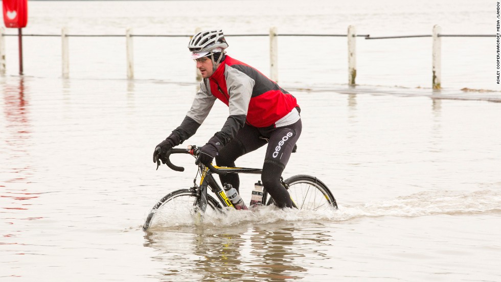 A cyclist pedals through coastal floodwaters in Storth, England, on January 4.